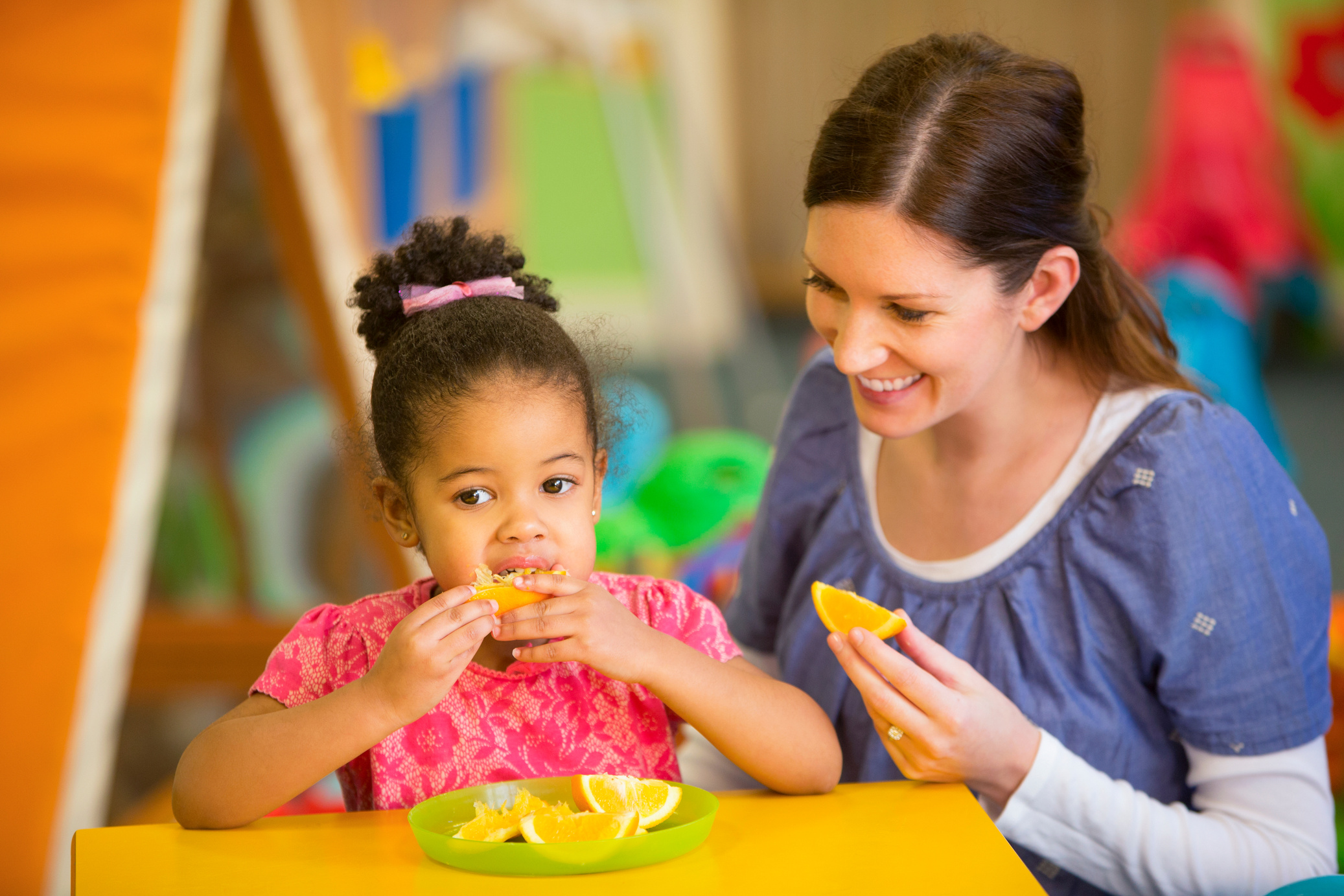 Nursery Teacher and Child Eating Oranges
